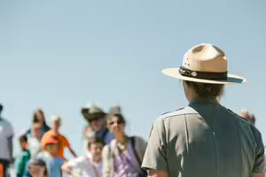 A woman in a ranger uniform faces a crowd of people