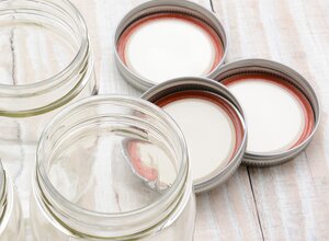 two-piece canning lids and rings next to clear jars