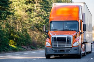 orange semi truck and trailer on a highway