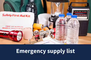 emergency supplies gathered together including a first aid kit, flashlight, batteries, radio, bottle of water, lantern, etc.