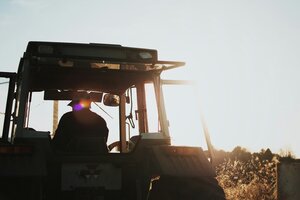 Tractor drives away into sunset. 