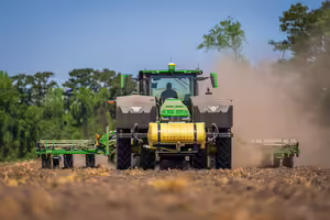 Green tractor drives through a field.