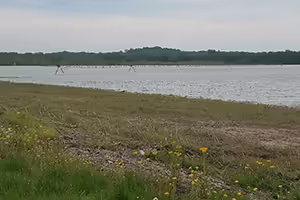 Large flooded farm field with standing water covering most of the ground and irrigation equipment partially submerged.