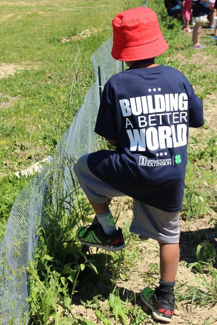 Youth in red hat and camp shirt digging in garden