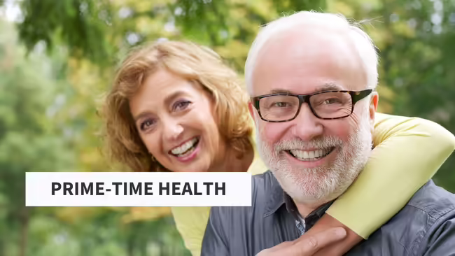 Female with arm draped around grey haired male wearing glasses.