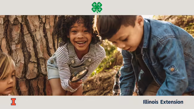 Young, smiling girl with magnifying glass and young boy in the woods