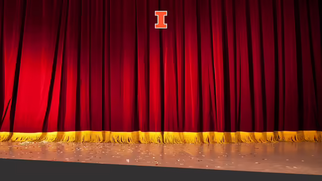 A red velvet stage curtain with yellow tassel trim on bottom of curtain.