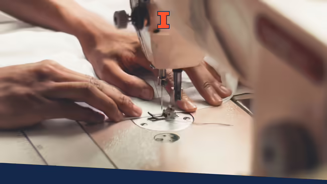 Hands slowly feeding a piece of material through the needle of the sewing machine.