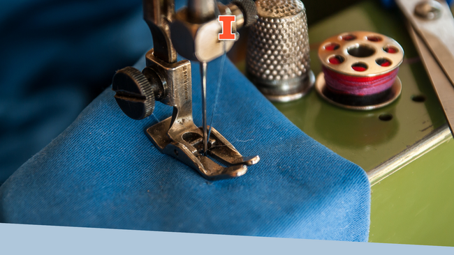 A blue piece of fabric being sewn through a sewing machine.