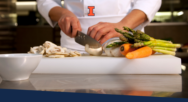 A chef preparing vegetables of a plastic cutting board that is sitting on a metal table.