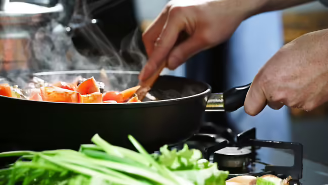 Image of a pan on a stovetop with food cooking and steaming