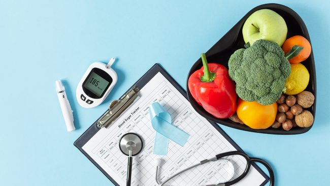 Image of clipboard, blue ribbon, bowl with fruits and vegetables, and diabetes management tools