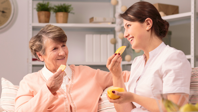 Image of older and younger woman eating snacks together