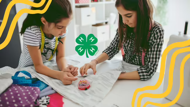 two girls pinning a pattern to fabric