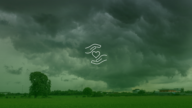Stormy skies over a farm with an icon of hands around a heart.