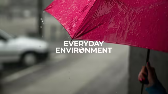 Person standing on the side of the street under a red umbrella.