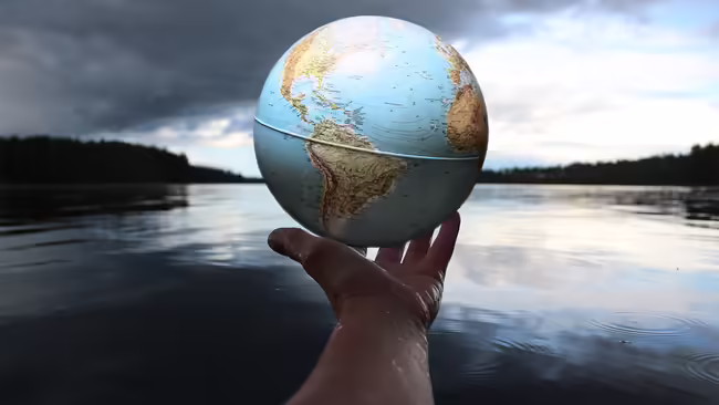 hand holding globe over lake