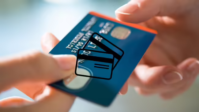A hand passing a credit card to a store clerk.