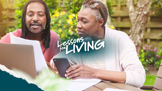 Adults looking at a laptop and paperwork outdoors.