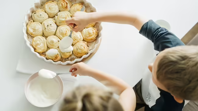 Children icing homemade cinnamon rolls
