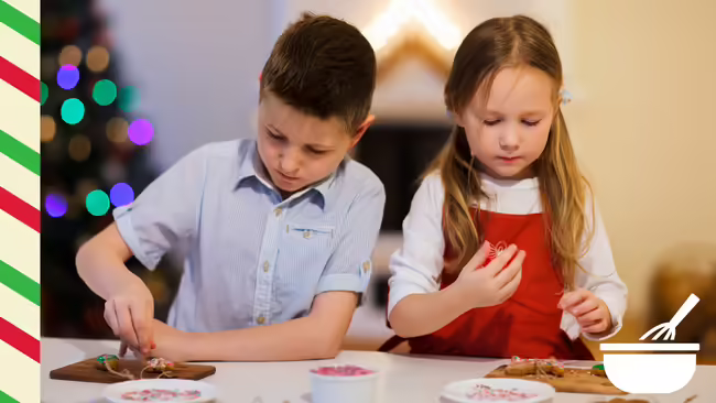 Two kids putting sprinkles on cookies.