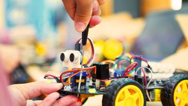 hands using screwdriver to adjust a robot