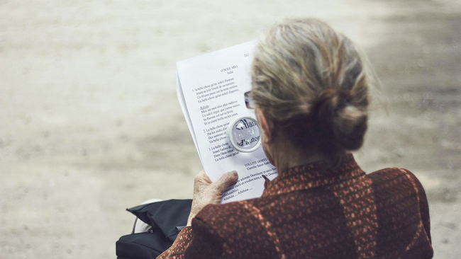 older person reading with a magnifying glass