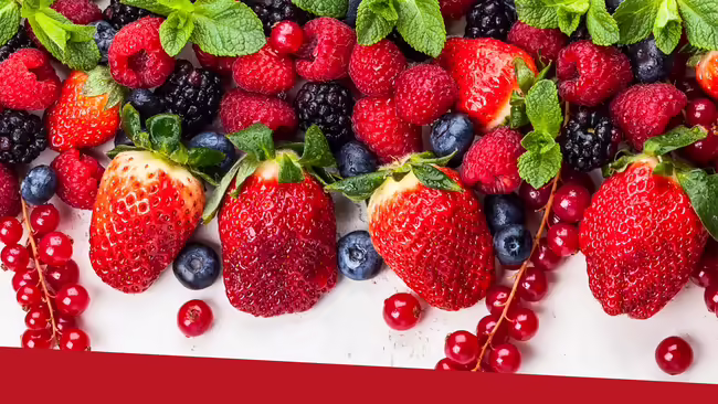 Strawberries, blueberries, raspberries, blackberries all mixed together on a white table.