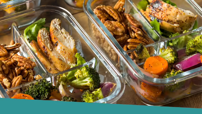 Meal prep containers full of chicken, vegetables, and walnuts.