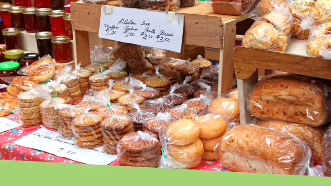 Baked good and homemade preserves and jams sitting on display being sold at a farmers market.