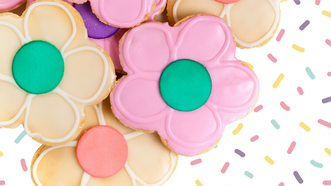 Colorful cookies decorated like cookies with sprinkles in the background.