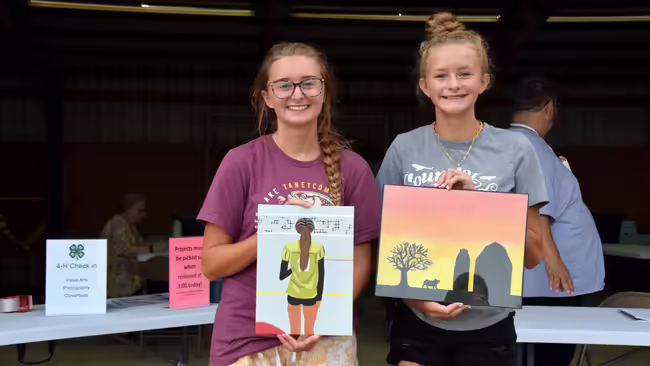 2 4-H members holding their art projects