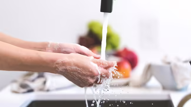 Washing hands with a bowl of food in the background