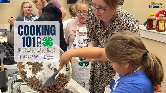 instructor helps 4-H member pour cooked hamburger out of pan and onto dish