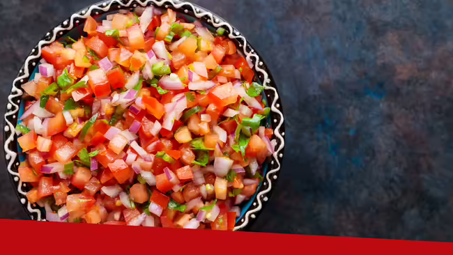 Pico de gallo sitting in a bowl on a gray colored background.