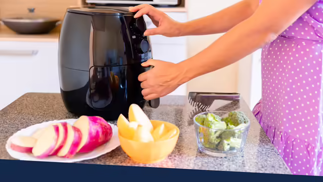 A women opening an air fryer on a kitchen counter to cook food in the air fryer.