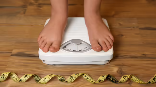 Child on scale with measuring tape on floor