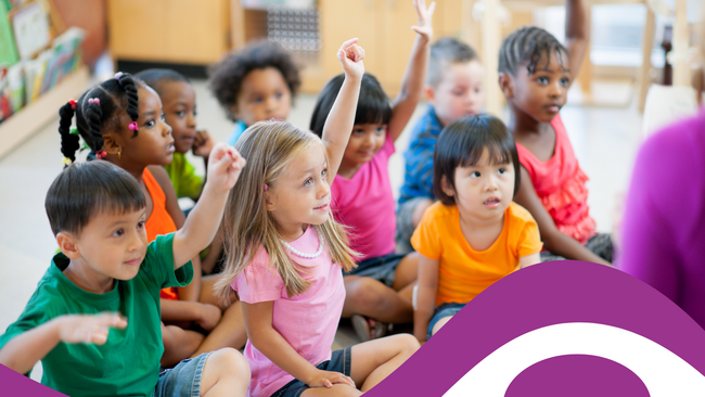 young children sitting on floor with hands raised