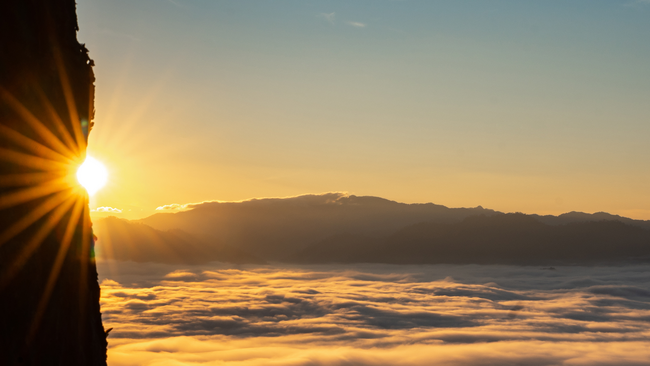 landscape with sun shining through mountains 