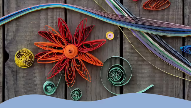 Paper quilling - colorful paper flowers on a wooden background.