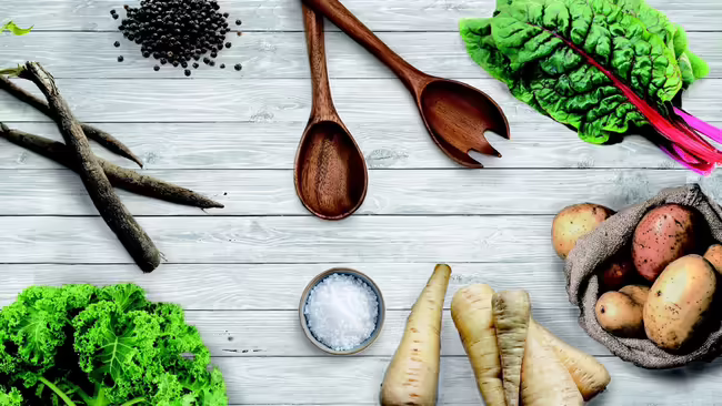 wooden spoons, salt and vegetables on a grey table