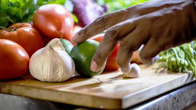 Photo of a hand reaching into a pile of fruits and vegetables 