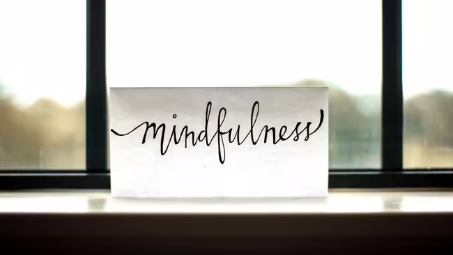 "Mindfulness" written on a card sitting on a shelf in front of a window