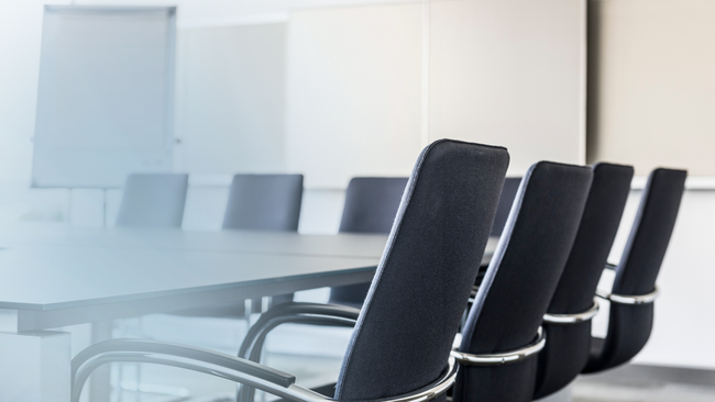 A meeting room with a large table and chairs in the room.