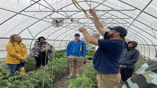 People In a Hoop house examining trellis structure