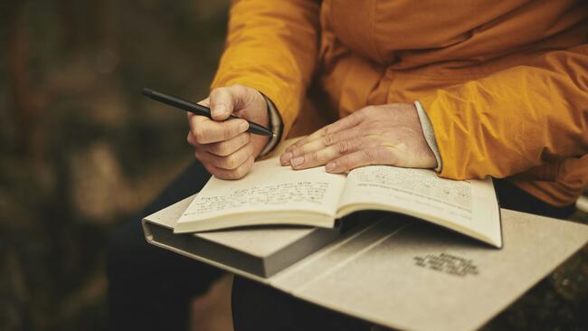 Elderly hands writing in a book