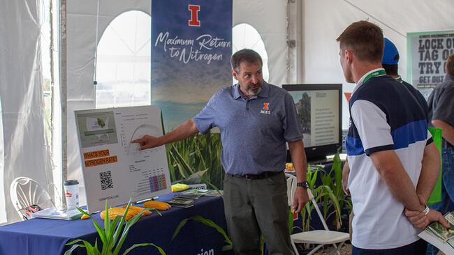 an Extension staff member discusses soil nitrogen with a person at a display booth