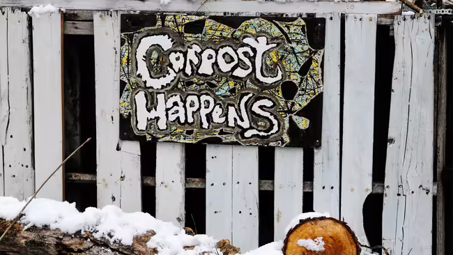 Compost happens sign on white wooden fence