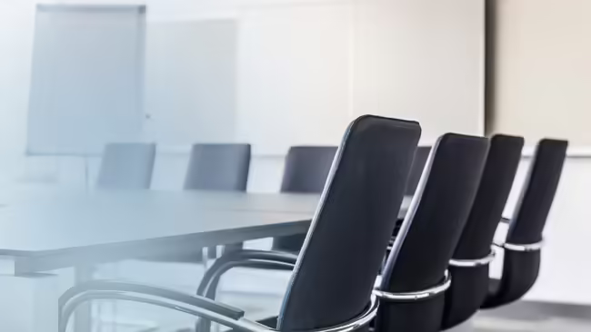 A conference room with chairs surrounding the table.