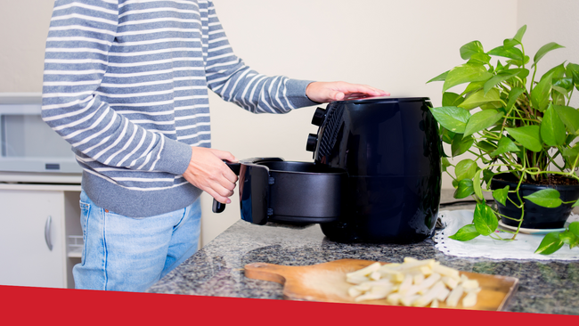 A man in a kitchen using an air fryer to cook food.